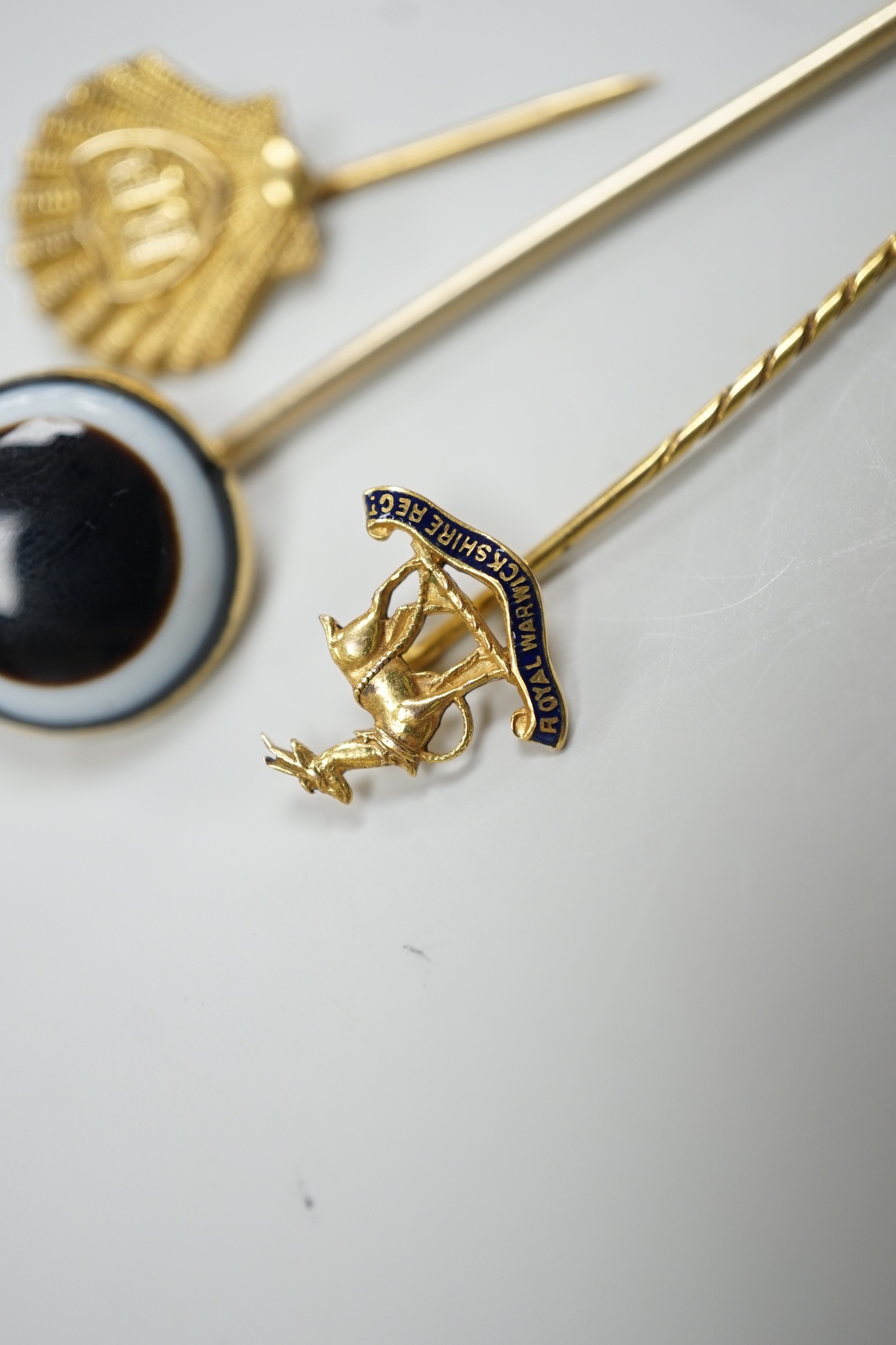A Victorian yellow metal and banded agate set stick pin, 84mm, a yellow metal Royal Warwickshire Regt. stick pin and a 1970's 9ct gold BP stick pin, gross weight 11.5 grams.